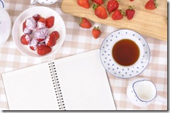 Strawberries with blank recipe book and check tablecloth
